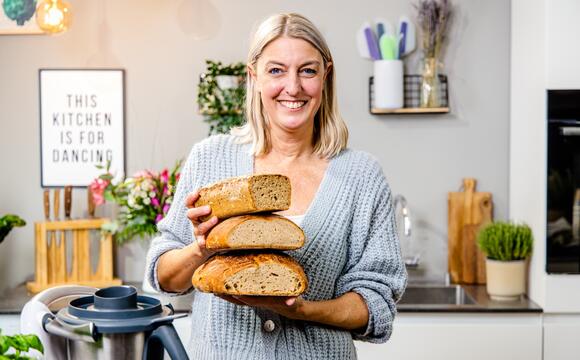 Blonde Frau mit 3 übereinandergestapelten Broten