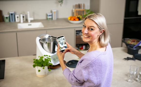 Frau mit blonden Haaren fotografiert mit Smartphone einen weißen Thermomix®
