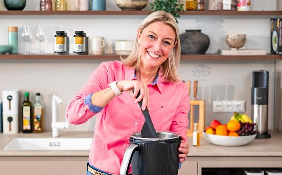 Blonde Frau in einer Küche mit Thermomix® TM7, schaut lächelnd in die Kamera