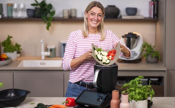Blonde Frau gibt Gemüse in den Thermomix®