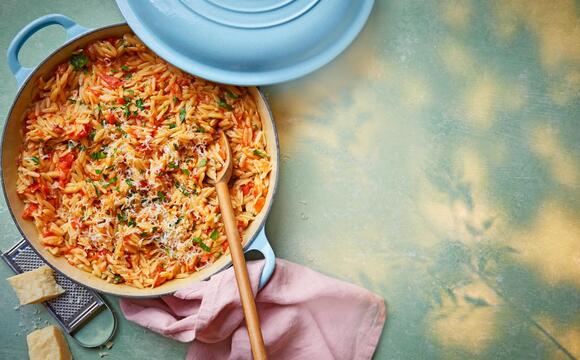 Orzo mit tomatensoße und Kräutern in einem hellblauen Topf, von oben fotografiert