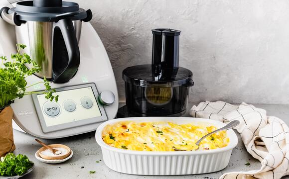 Der Thermomix® TM6, daneben der Wunder Slicer Aufsatz und eine Auflaufform mit Kartoffelgratin