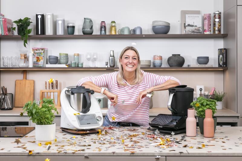 Blonde Frau mit zwei Thermomix® Geräten in einer Küche voller Konfetti