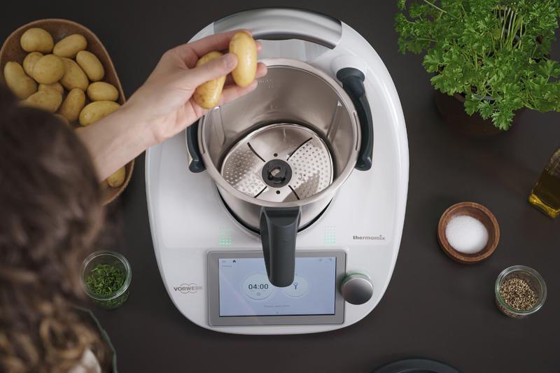 Hände, die Kartoffeln in Thermomix® geben, von oben fotografiert