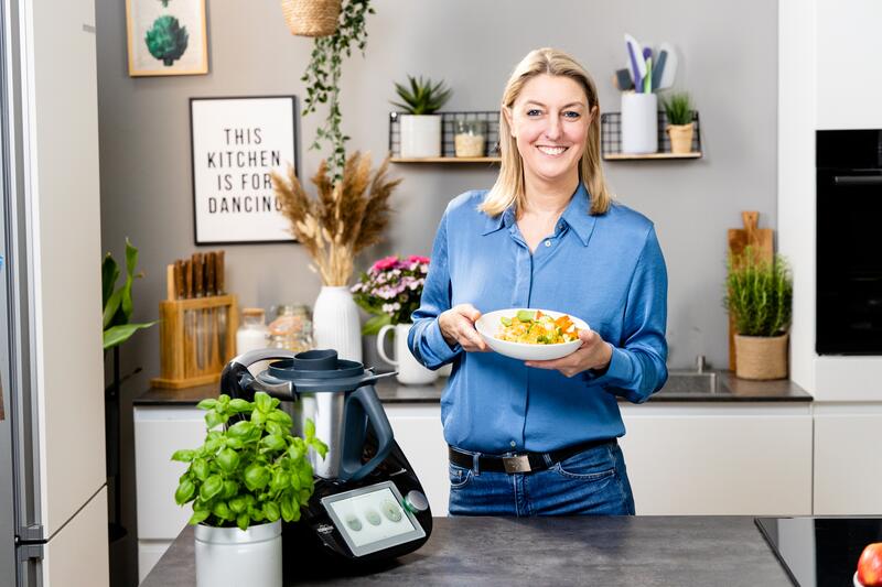 Frau mit blonden Haaren in Küche mit schwarzem Thermomix®