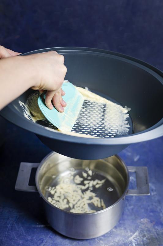 Spätzle-Teig wird mit einem Teigspatel durch den Varoma® geschabt.
