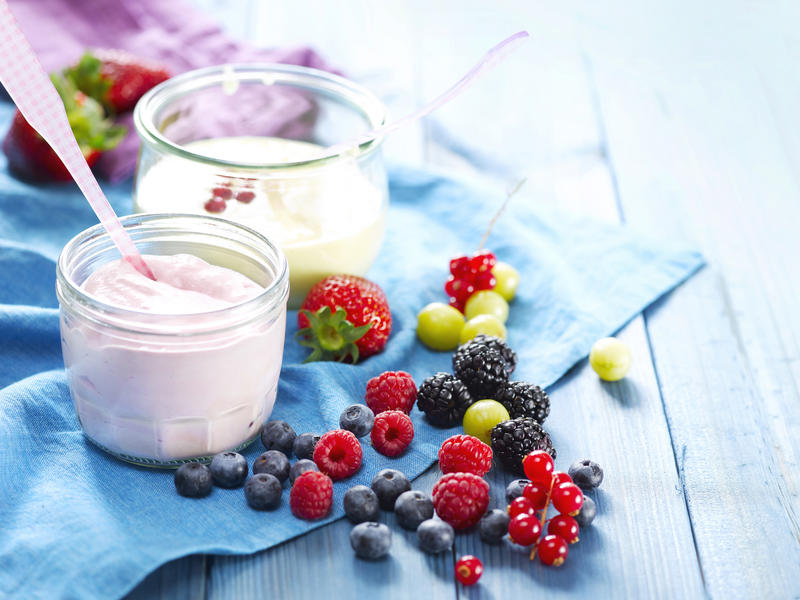 Erdbeer-Ricotta-Creme in einem Glas. Davor liegen Beeren verteilt.