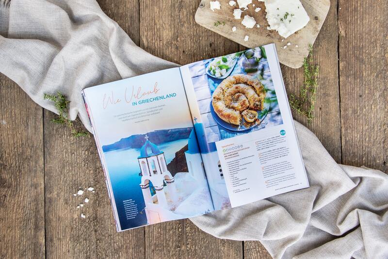 Mein ZauberTopf Magazin liegt mit der Urlaubsrezepteseite aufgeschlagen auf einem Holztisch