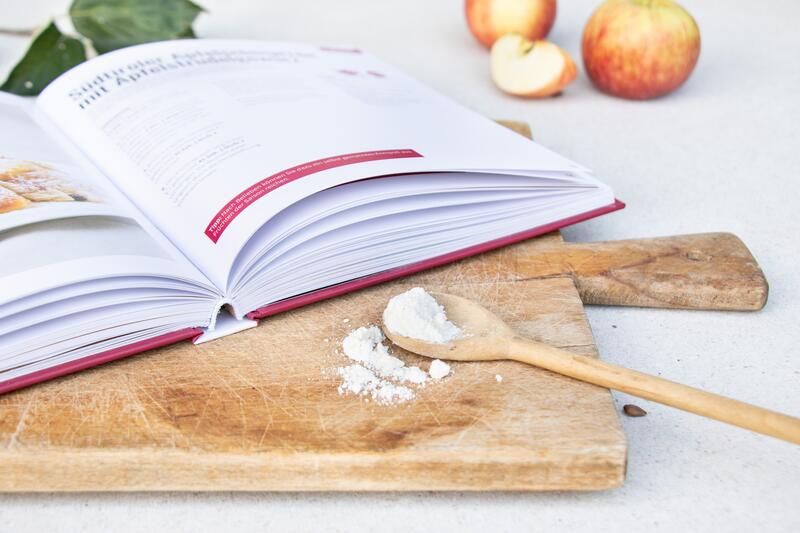 Das Hardcover-Kochbuch Südtirol mixt! liegt aufgeschlagen auf einem Brett