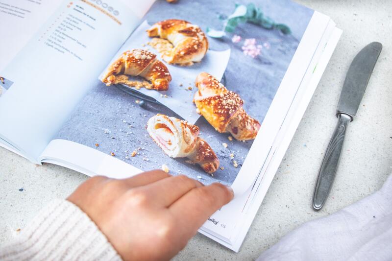 Eine Hand blättert durch das Brotbackbuch von mein ZauberTopf