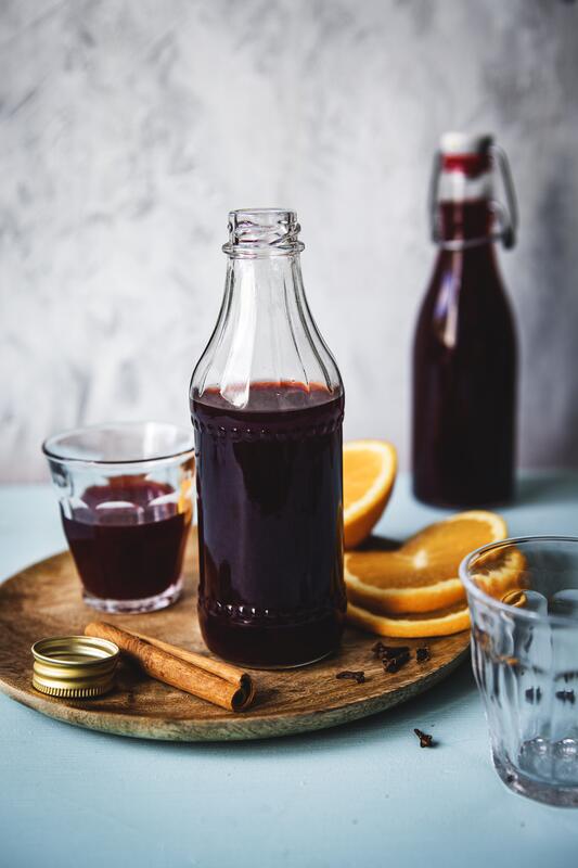 Glühweinlikör in Flasche und Glas auf einem Holzbrett