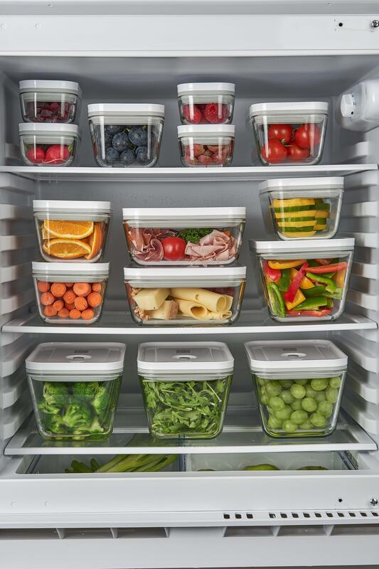 Frische Lebensmittel in Aufbewahrungsdosen übereinander gestapelt im Kühlschrank