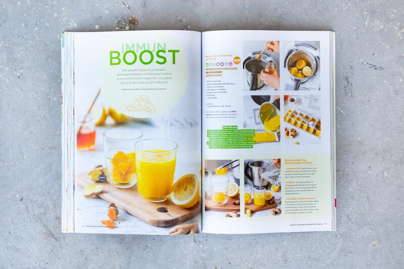 In der aufgeschlagenen mein zauberTopf gold-Edition ist ein schrittweise erklärtes Immun-Boost-Rezept zu sehen.