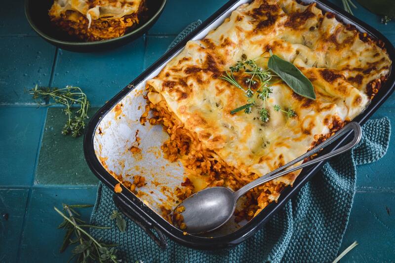 Lasagne in einer Auflaufform, darin liegt ein Löffel