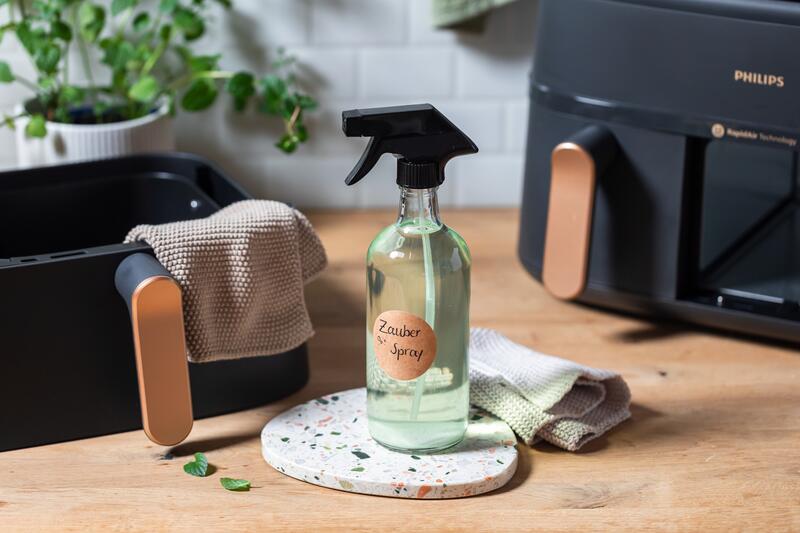 Flasche mit Zauberspray Reinigungsspray steht vor dem Airfryer