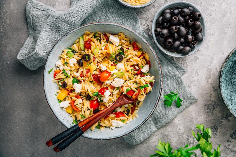 Orzo-Salat mit Paprika und Oliven von oben in einer Schüssel fotografiert