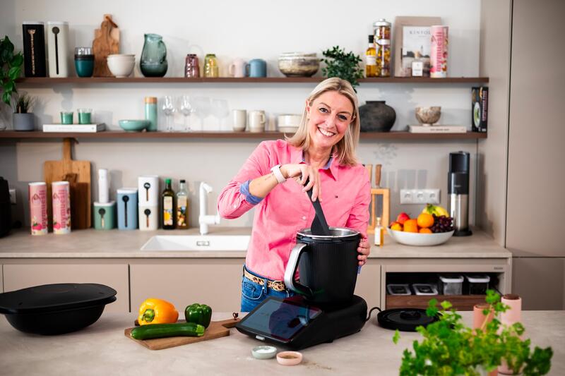 Eine blonde Frau rührt mit dem Spatel im Thermomix® TM7