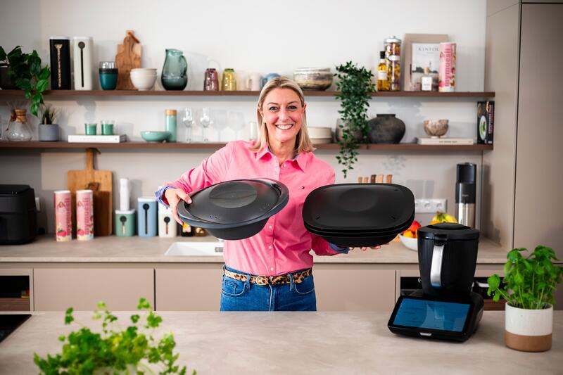 Eine Frau hält den Varoma® des Thermomix® TM6 und TM7 nebeneinander zum Vergleich