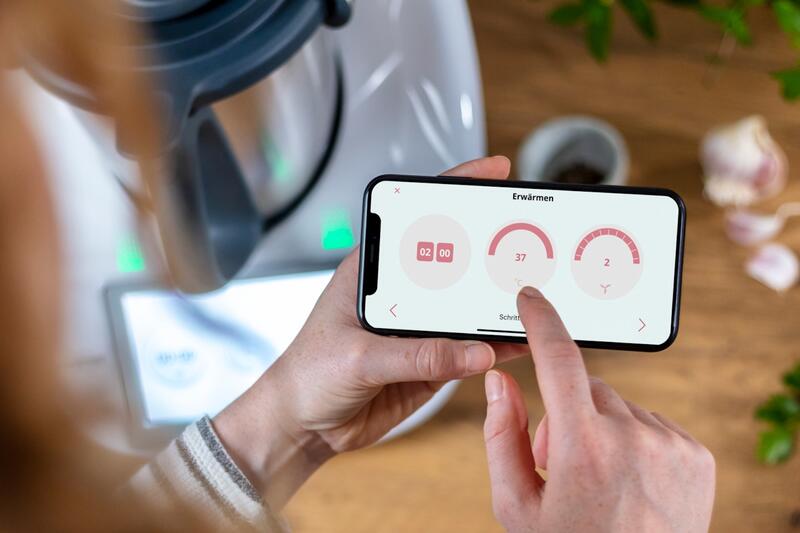 Der Kochmodus des ZauberTopf-Club auf dem Display eines Handys, im Hintergrund ein Thermomix®