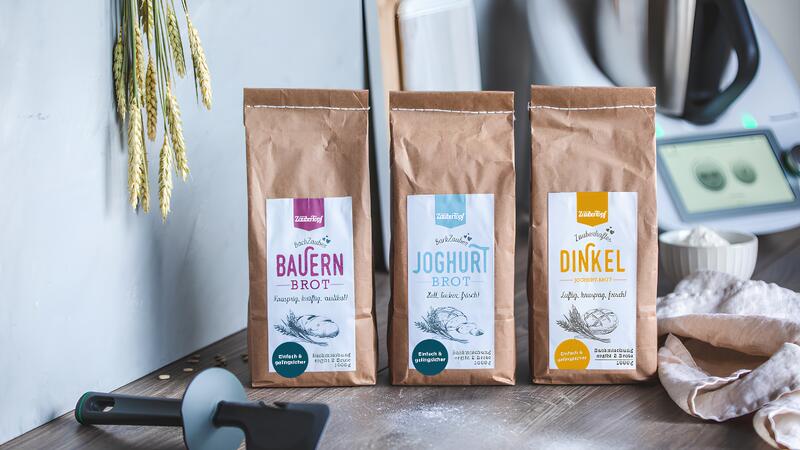 Drei Brotbackmischungen in braunen Tüten, im Hintergrund der Thermomix®