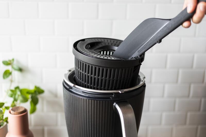 Jemand hebt mit dem Spatel den Garkorb aus dem Mixtopf des Thermomix®