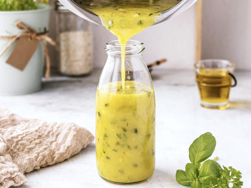 Salatdressing fließt aus dem Mixtopf des Thermomix® in eine Flasche