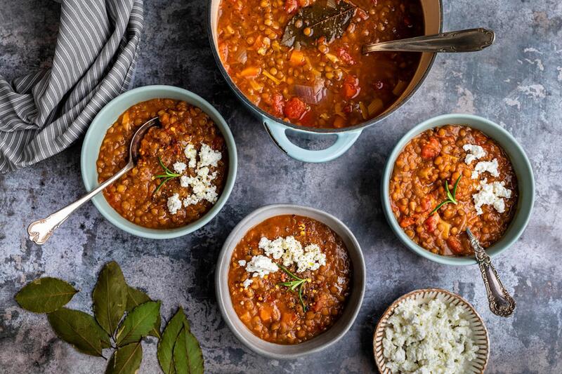 Ein Topf und drei Schalen mit Linsensuppe von oben fotografiert