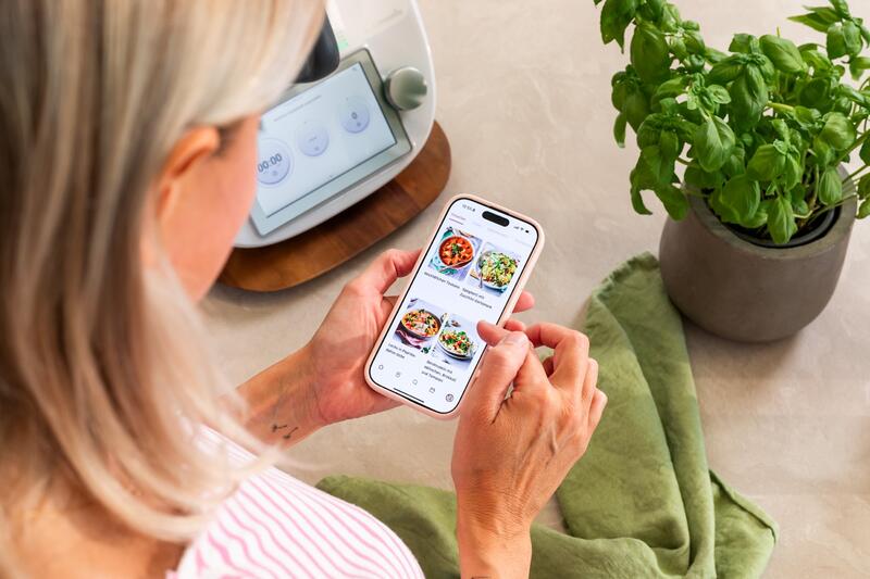 Blick über die Schulter einer blonden Frau, die den ZauberTopf Club auf ihrem Smartphone aufgerufen hat