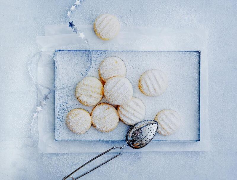 Helle, runde Plätzchen mit Puderzucker bestäubt auf einem Gitter
