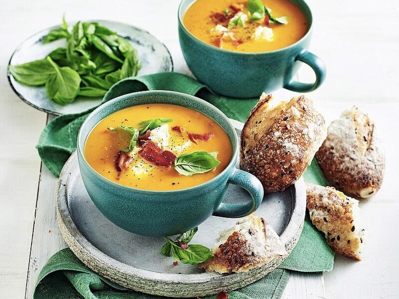 Zwei Schalen mit Tomatensuppe, daneben ein Stück Brot