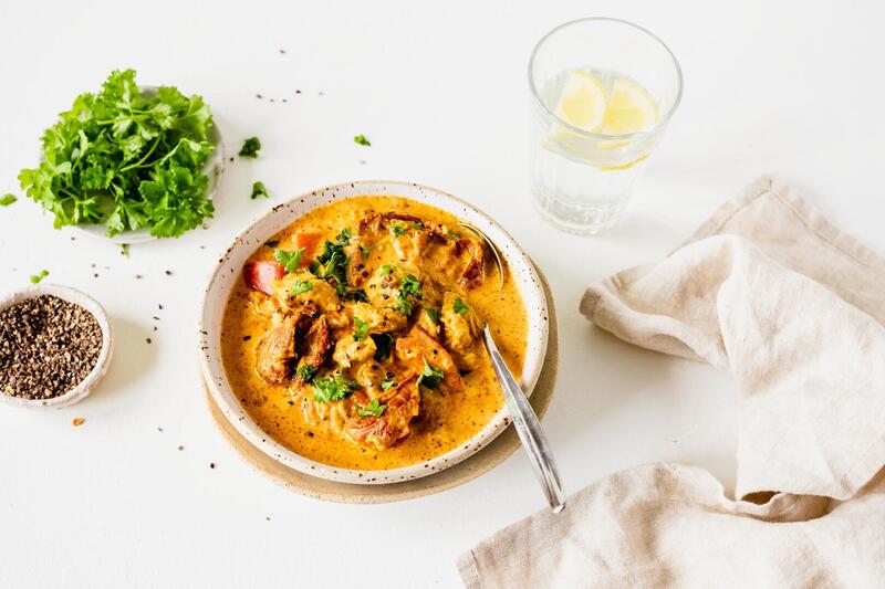 Ein Teller mit roter Suppe mit Hähnchen darin