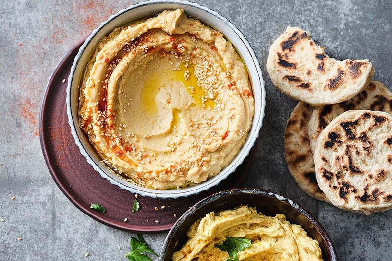 Eine Schüssel mit einem cremefarbenen Dip von oben fotografiert, daneben Fladenbrot