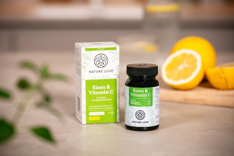 Ein Glas mit Eisen und Vitamin C Tabletten, im Hintergrund Zitronen