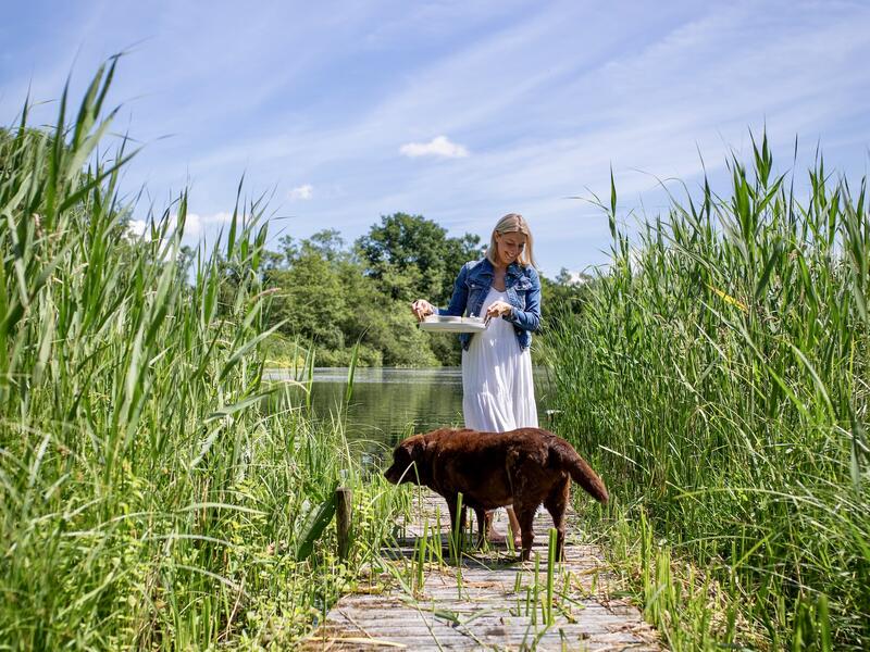 Blonde Frau auf einem Steg mit einem Hund