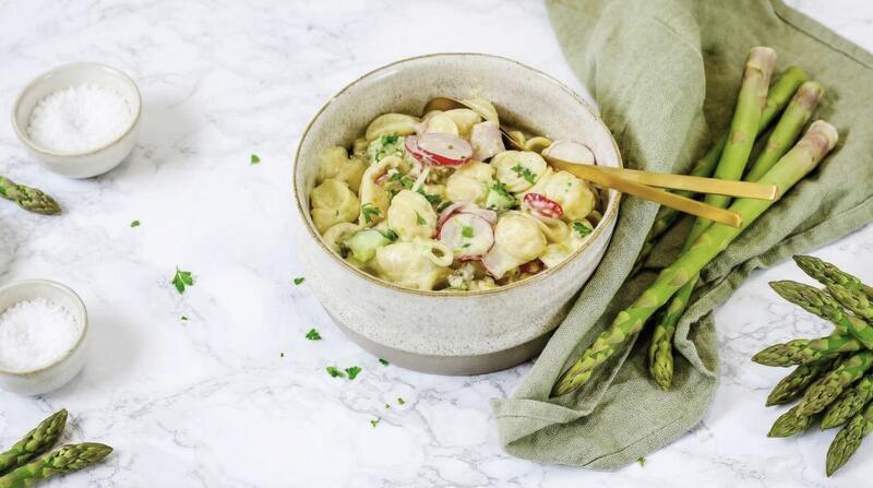 Eine Schale mit Nudelsalat, daneben grüner Spargel