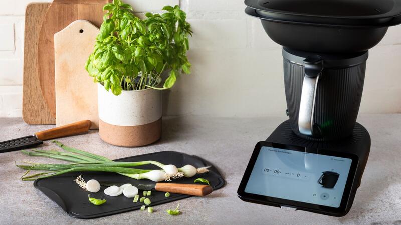 Schwarzes Schneidebrett mit Gemüse darauf, daneben ein Thermomix®