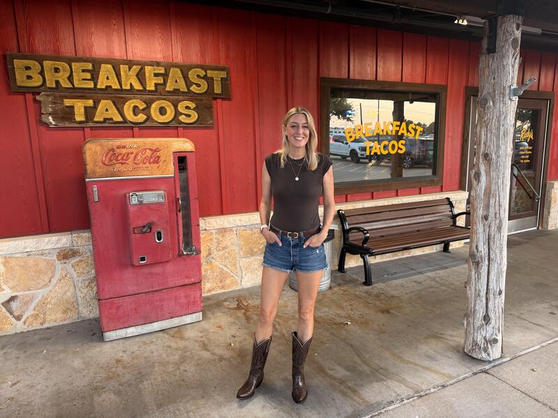 Blonde Frau mit Shorts und Cowboy-Stiefeln vor einem Taco-Restaurant