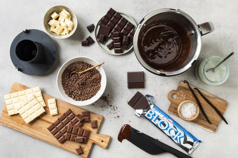 Thermomix® Mixtopf und verschiedene Sorten Schokolade von oben fotografiert