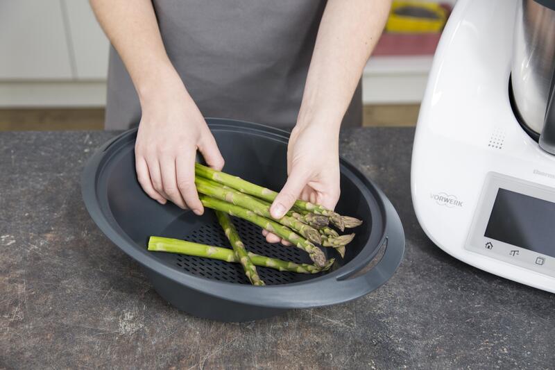Grüner Spargel wird von zwei Händen in den Varoma® gelegt.