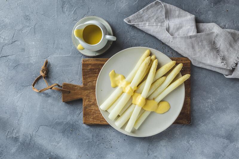 Weißer Spargel mit Sauce Hollandaise auf weißem Teller