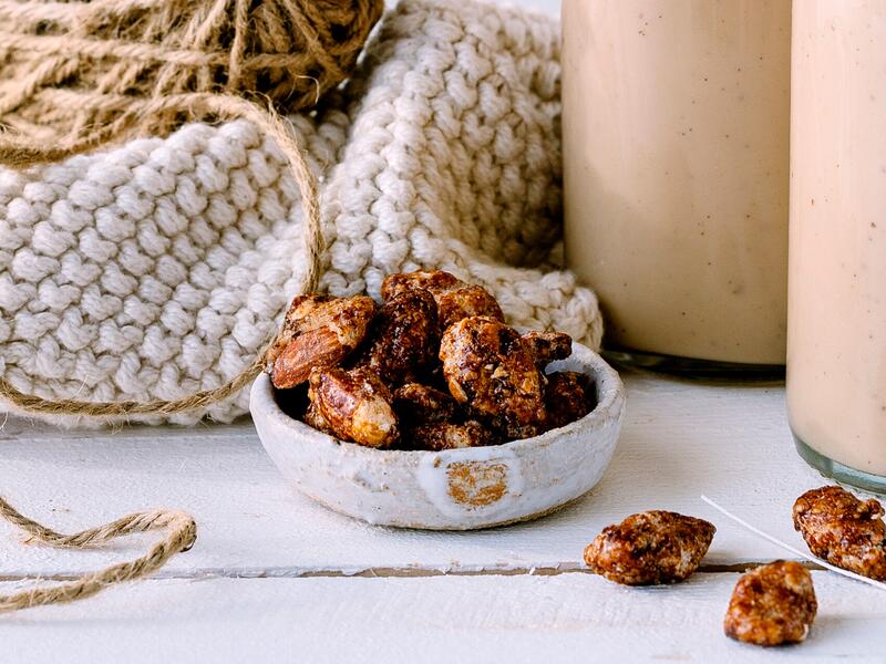 Eine helle Schale mit gebrannten Mandeln aus dem Thermomix® auf weißem Untergrund