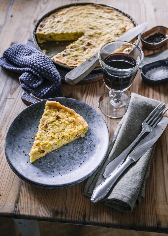 Einzelnes Stück Quiche Lorraine aus dem Thermomix® auf dunklem Teller.