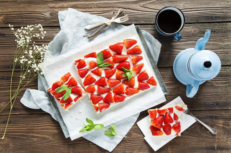 Erdbeer-Schmand-Kuchen aus dem Thermomix® auf dunklem Holztisch.