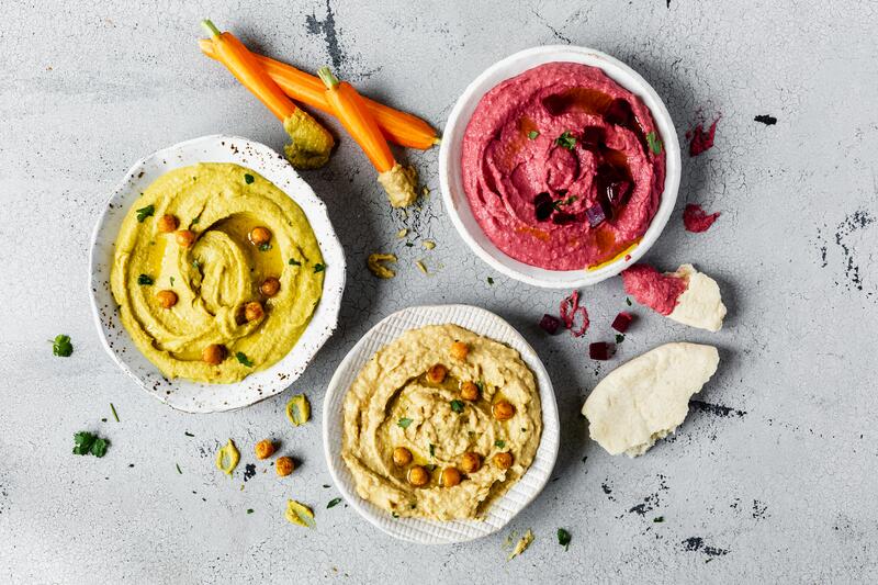 Hummus in einer Schüssel mit Sesam, Öl und Basilikum.