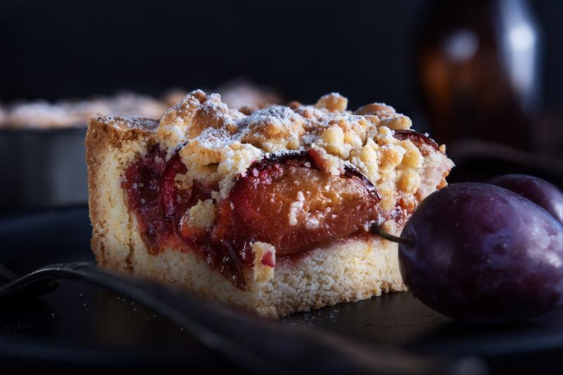 Stück Pflaumenkuchen mit Hefeteig, Streuseln und Puderzucker