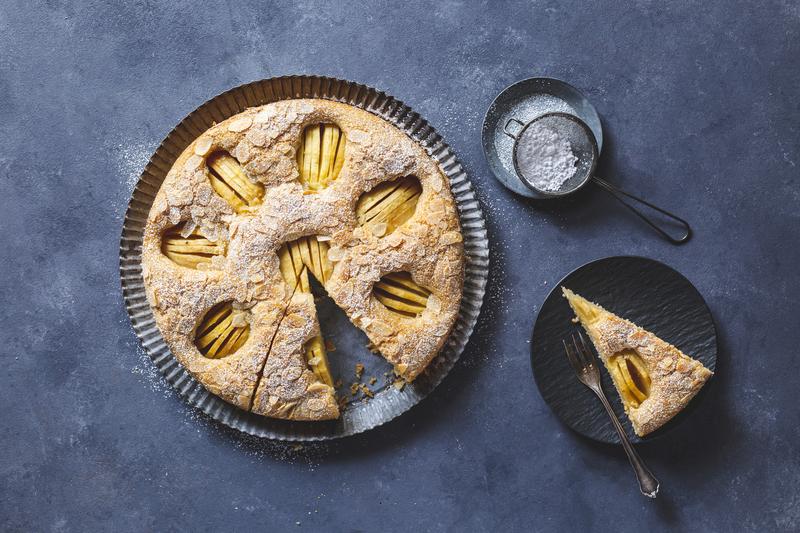 Angeschnittener versunkener Apfelkuchen auf dunklem Untergrund von oben fotografiert