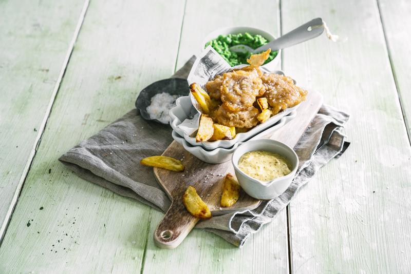 Fritierter Fisch und Kartoffelecken mit hellem Dip in Schale