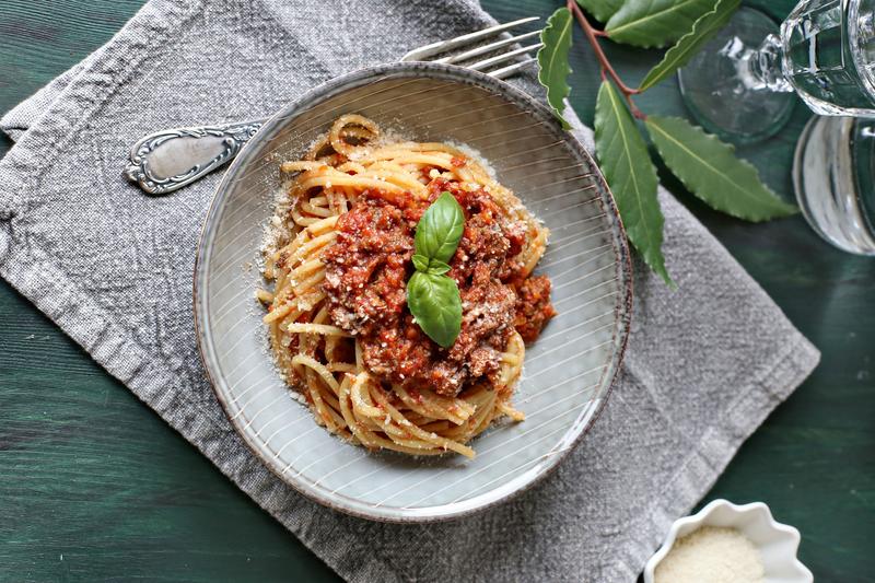 Spaghetti Bolognese auf einem grauen Teller mit Basilikum garniert
