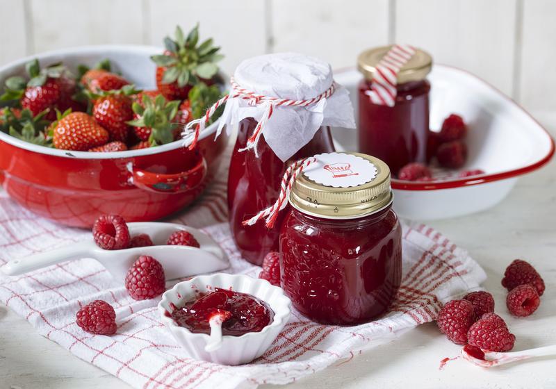 Marmeladengläser mit rotem Gelee mit angelegten Erdbeeren und Himbeeren