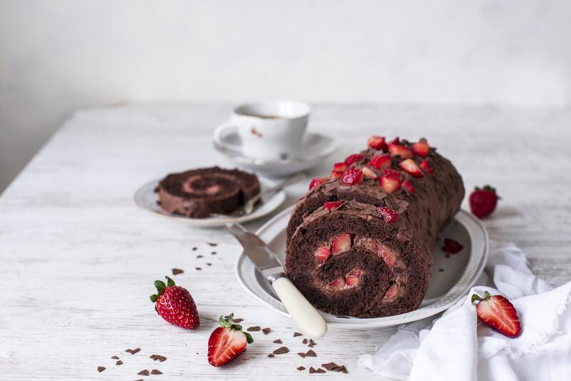 Schokoladen-Erdbeer-Biskuitrolle auf einem Teller.
